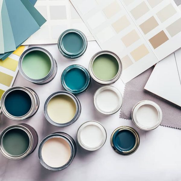 Open paint cans and color swatches on a table, featuring various shades of green, blue, and neutral tones.
